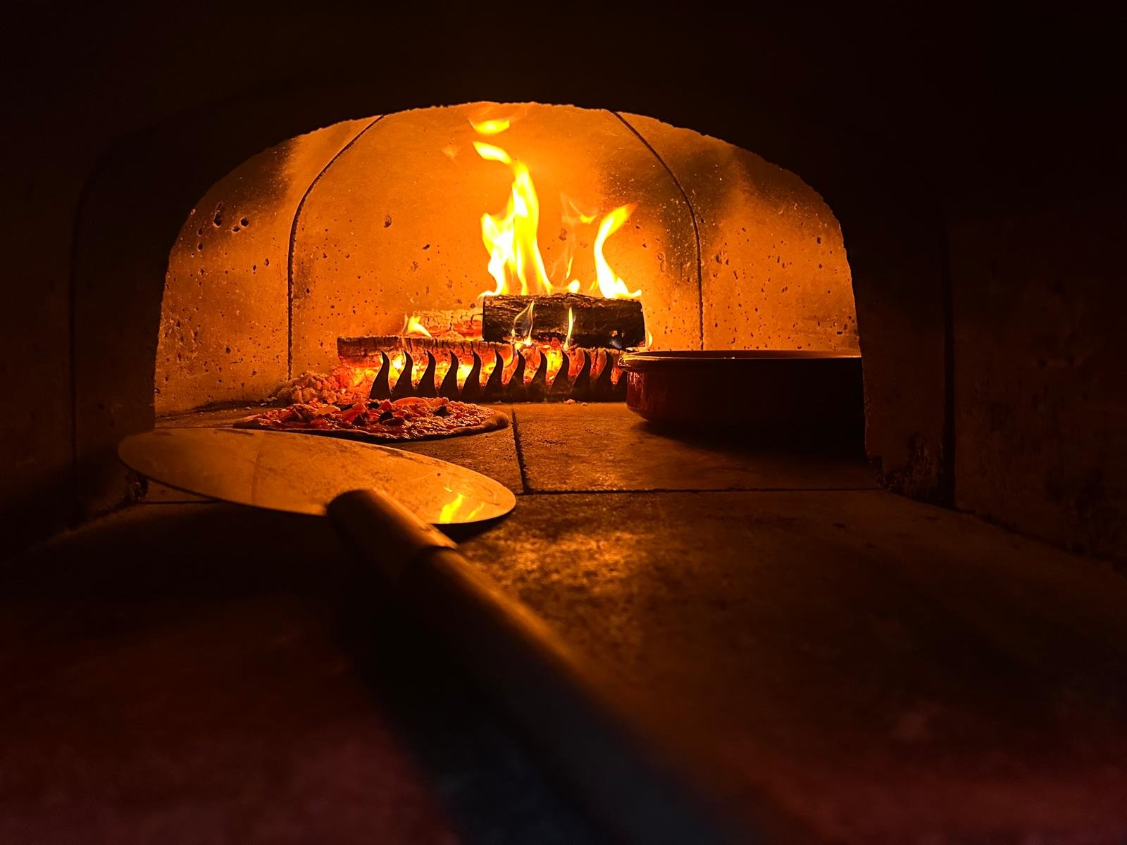 Pizza cooking inside the wood-fired oven