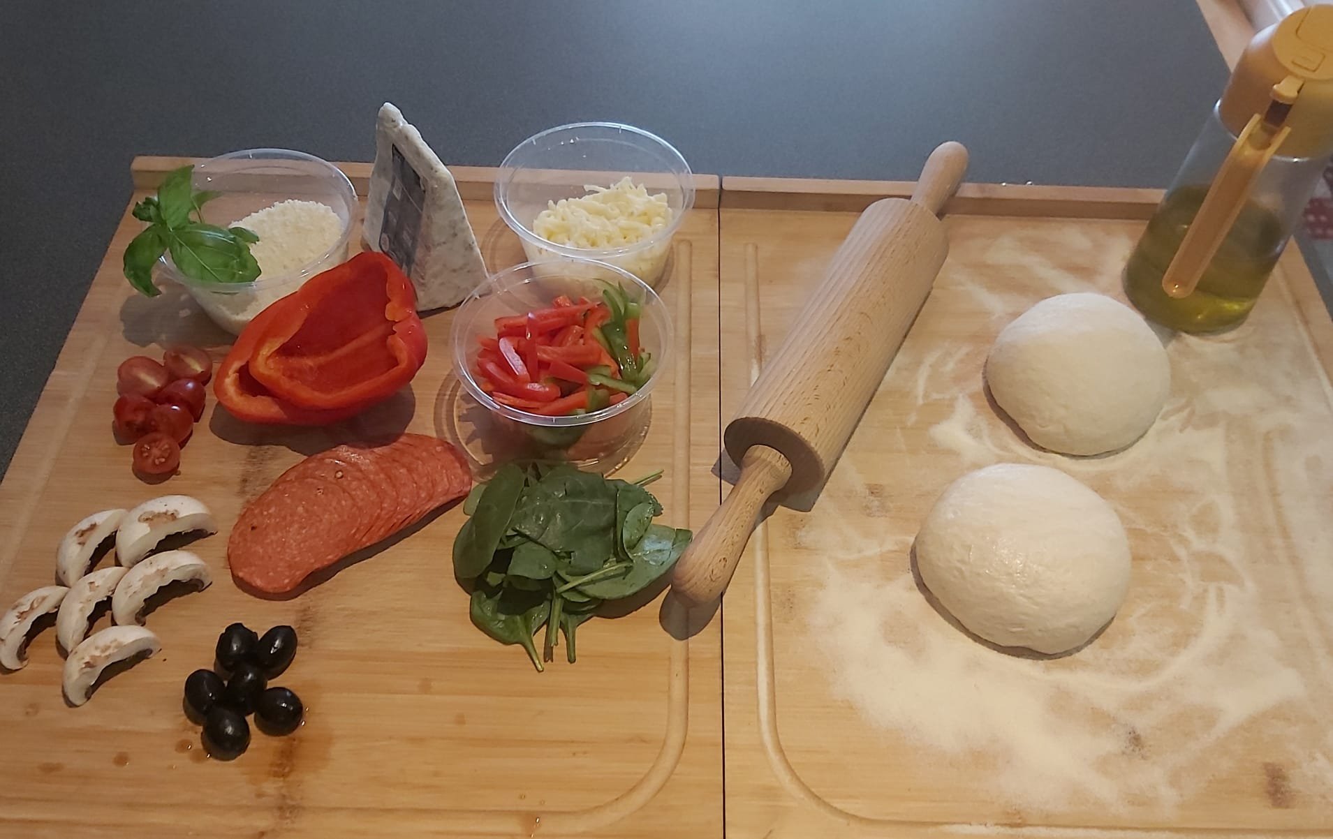 Fresh pizza dough balls on wooden board with toppings